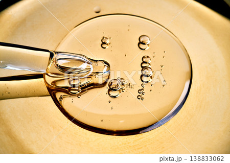 Pipette dripping golden oil on glossy surface 138833062