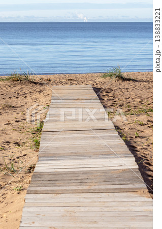 A wooden boardwalk leads across coastal sandy dunes A wooden boardwalk leads across coastal sandy dunes 138833221