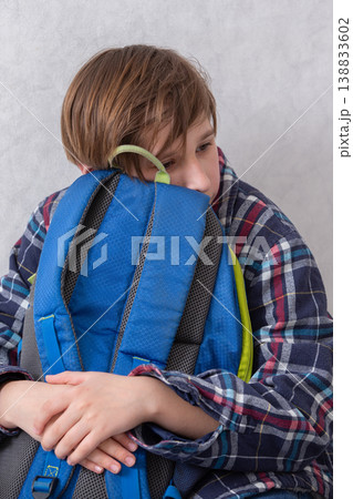 Child resting with a blue backpack while sitting indoors in a casual and comforting setting during a quiet afternoon 138833602