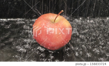Water splashes over a fresh apple on a black surface during a clean routine 138833724