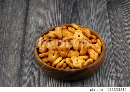 Spicy triangle crackers in a wooden bowl on rustic wood background, crunchy savory snack food 138833812
