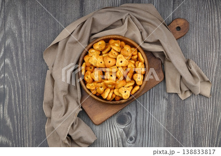 Spicy triangle crackers in a wooden bowl on rustic wood background, crunchy savory snack food 138833817