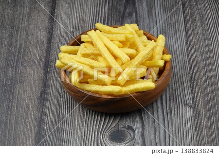 Steak flavored corn sticks in wooden bowl on rustic wood background, crunchy barbecue snack food 138833824