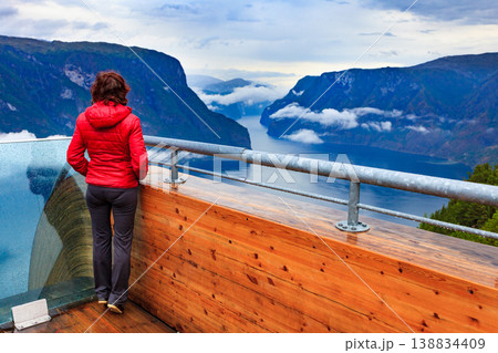 Tourist enjoying fjord view on Stegastein viewpoint Norway Tourist enjoying fjord view on Stegastein viewpoint Norway 138834409