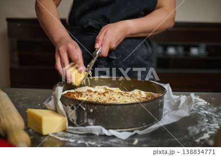 Grating cheese over lasagna in baking dish before baking 138834771