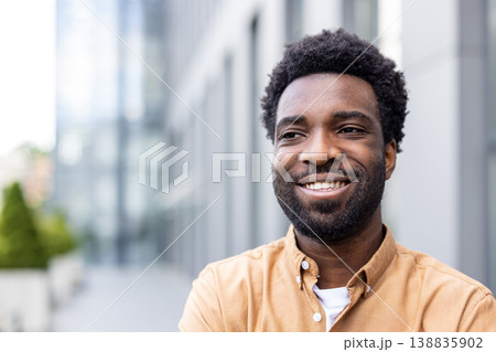 Young man with a warm smile looking away, expressing happiness and confidence while standing outdoors in a modern city environment, conveying professionalism and success Young man with a warm smile looking away, expressing happiness and confidence while standing outdoors in a modern city environment, conveying professionalism and success 138835902