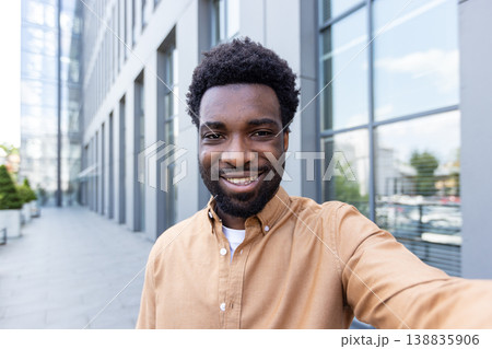 Young smiling black entrepreneur takes a confident outdoor selfie in a modern urban setting, candid headshot with office buildings in the bright daytime background, authentic and upbeat Young smiling black entrepreneur takes a confident outdoor selfie in a modern urban setting, candid headshot with office buildings in the bright daytime background, authentic and upbeat 138835906