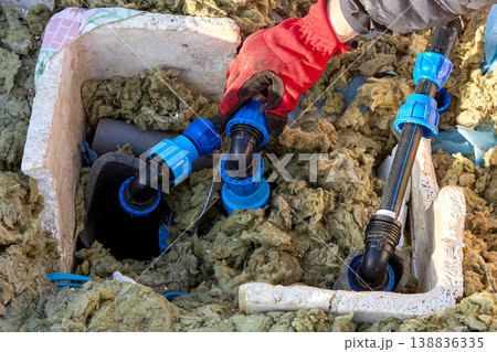 Homeowner tightening plastic compression fitting nut during installation of distribution piping in artesian well pit. 138836335