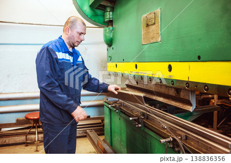 Metal Formation by Hydraulic Press. Factory Worker at Work. Worker operating metal press machine at workshop. 138836356