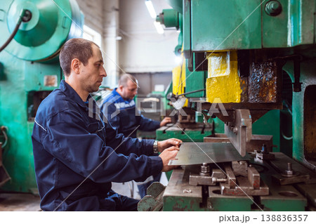 Metal Formation by Hydraulic Press. Factory Worker at Work. Worker operating metal press machine at workshop. Metal Formation by Hydraulic Press. Factory Worker at Work. Worker operating metal press machine at workshop. 138836357