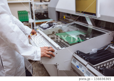 Factory of electronic products. The engineer controls technological process of soldering and assembling the components of the microcircuit on printed circuit board. Automatic soldering machine. Factory of electronic products. The engineer controls technological process of soldering and assembling the components of the microcircuit on printed circuit board. Automatic soldering machine. 138836365