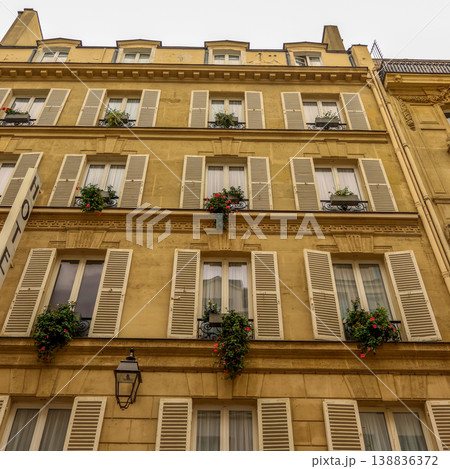 Parisian building facade showcasing traditional architecture, windows with open shutters, balconies, and vibrant flower boxes Parisian building facade showcasing traditional architecture, windows with open shutters, balconies, and vibrant flower boxes 138836372