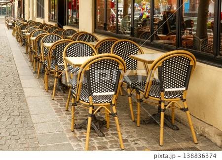 Parisian sidewalk cafe preparing for customers, famous chairs and tables lining a historic street in Paris, France Parisian sidewalk cafe preparing for customers, famous chairs and tables lining a historic street in Paris, France 138836374