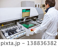 Factory of electronic products. The engineer controls technological process of soldering and assembling the components of the microcircuit on printed circuit board. Automatic soldering machine. 138836382