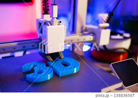 A close-up shot of a 3D printer in action, meticulously crafting bright blue numbers with intricate lattice patterns on its build plate A close-up shot of a 3D printer in action, meticulously crafting bright blue numbers with intricate lattice patterns on its build plate 138836507