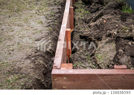 Aligning Wooden Raised Garden Bed Frame Inside Prepared Soil Trench Outdoors Aligning Wooden Raised Garden Bed Frame Inside Prepared Soil Trench Outdoors 138836593