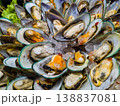 High angle view of cooked green mussels on shells arranged in a circle on ice. Seafood platter on display at a market. Healthy mediterranean food. 138837081