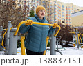 Senior woman exercising on outdoor fitness machine in winter 138837151
