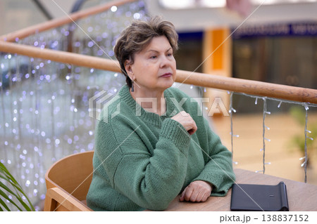 Mature woman working on laptop in shopping mall interior Mature woman working on laptop in shopping mall interior 138837152