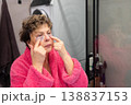 Applying under eye patches mature woman skincare routine in bathroom 138837153