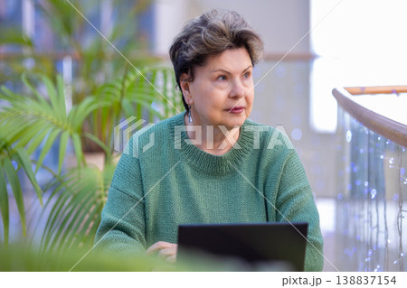 Mature woman working on laptop in shopping mall interior Mature woman working on laptop in shopping mall interior 138837154