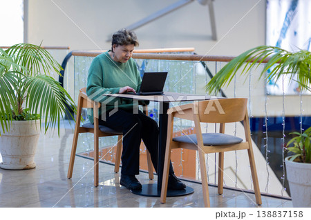 Mature woman working on laptop in shopping mall interior 138837158