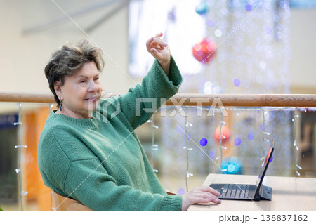 Mature woman working on laptop in shopping mall interior Mature woman working on laptop in shopping mall interior 138837162