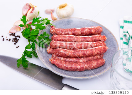 Plate of raw longaniza wit greens, garlic and spices prepared for cooking 138839130