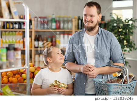 Young dad and tween son choosing food together in supermarket 138839248