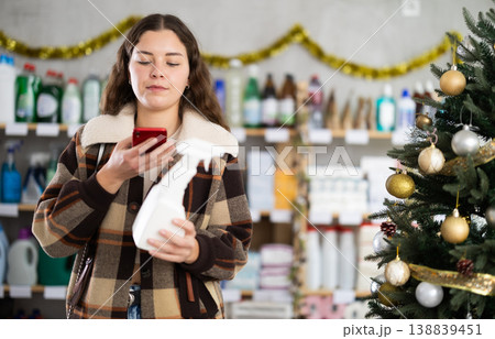 In Christmas decorated shop, woman client scanning QR code on package paint remover In Christmas decorated shop, woman client scanning QR code on package paint remover 138839451