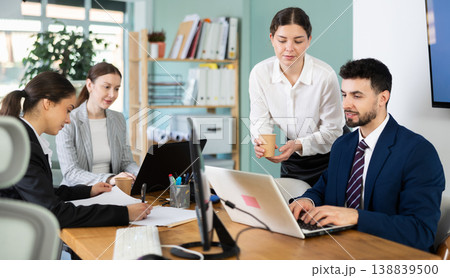 Young woman bringing coffee to male colleague in office 138839500