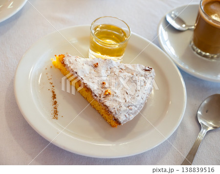 Slice of Tarta de Santiago with coffee with milk and wine Slice of Tarta de Santiago with coffee with milk and wine 138839516