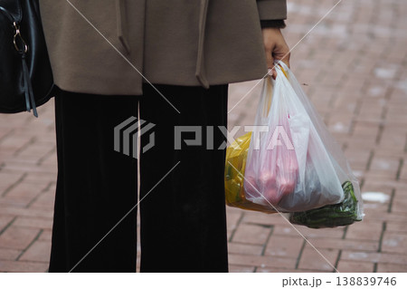 Woman holding grocery bags on city street during daytime 138839746