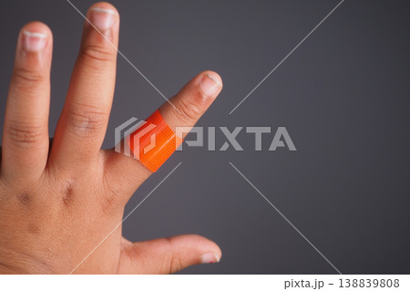 Injured finger with an orange bandage on a hand Injured finger with an orange bandage on a hand 138839808