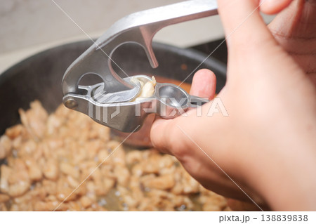 Cooking with a garlic press in a home kitchen setting Cooking with a garlic press in a home kitchen setting 138839838