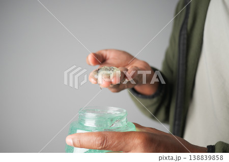 Man holds hair gel from jar in hands during personal care routine Man holds hair gel from jar in hands during personal care routine 138839858