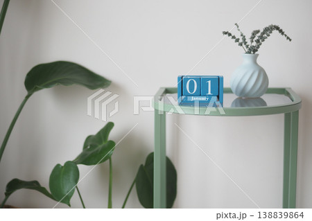 Table displays calendar and vase with plant on January first Table displays calendar and vase with plant on January first 138839864
