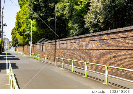 緑に囲まれた長いレンガ塀と静かな道路風景 緑に囲まれた長いレンガ塀と静かな道路風景 138840108