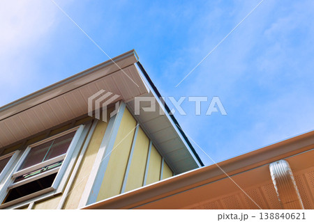 Bright blue sky above house with yellow siding slanted roof edges gutters Bright blue sky above house with yellow siding slanted roof edges gutters 138840621