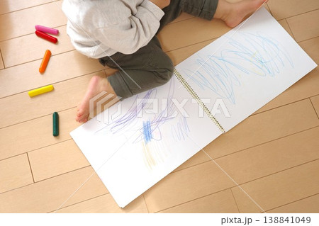 家の床でスケッチブックにクレヨンでお絵かきする子供 家の床でスケッチブックにクレヨンでお絵かきする子供 138841049