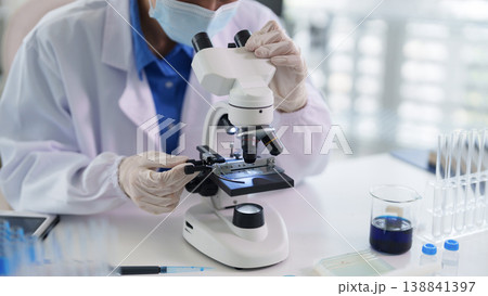 Adult Asian researcher using microscope examining samples conducting scientific experiment laboratory medical discovery innovative healthcare solutions 138841397