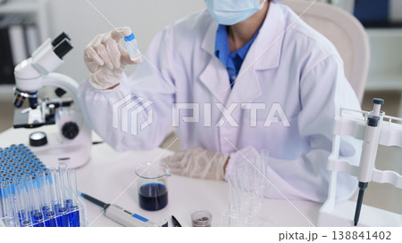 Adult Asian scientist researcher holds chemical sample vial laboratory testing medical discovery innovation development healthcare research facility scientific experiment Adult Asian scientist researcher holds chemical sample vial laboratory testing medical discovery innovation development healthcare research facility scientific experiment 138841402