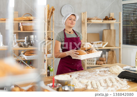 Woman seller holding basket with homemade bread in bakery Woman seller holding basket with homemade bread in bakery 138842080