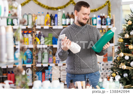 On New Year Eve, man choose and buy liquid washing powder and tile cleaner spray On New Year Eve, man choose and buy liquid washing powder and tile cleaner spray 138842094