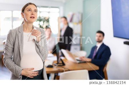 Distressed pregnant woman standing with sad expression in office 138842154