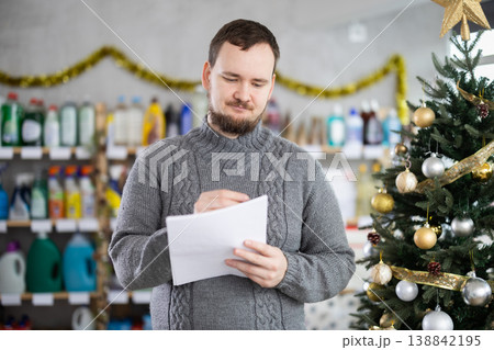 Middle-aged man restocking using paper in store with New Year decoration Middle-aged man restocking using paper in store with New Year decoration 138842195