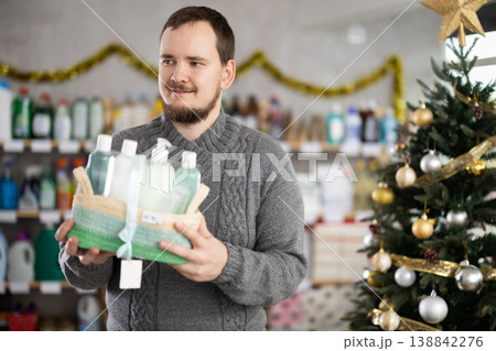 Interested nice bearded man choosing gifts for New Year in household department of supermarket Interested nice bearded man choosing gifts for New Year in household department of supermarket 138842276