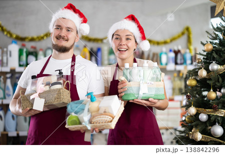 Cheerful sellers in Santa hats offering cleaning supplies and toiletries in store 138842296