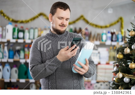 Checking expiration date of shower gel or champoo - male shopper scans QR code on label of shower gel or champoo using smartphone 138842361