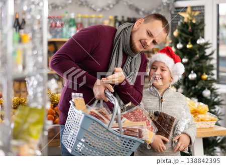 Dad and son are choosing products for New Year celebration in supermarket Dad and son are choosing products for New Year celebration in supermarket 138842395